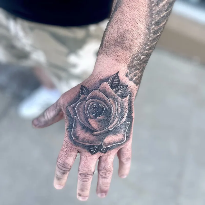 black and grey rose hand tattoo by Jesse